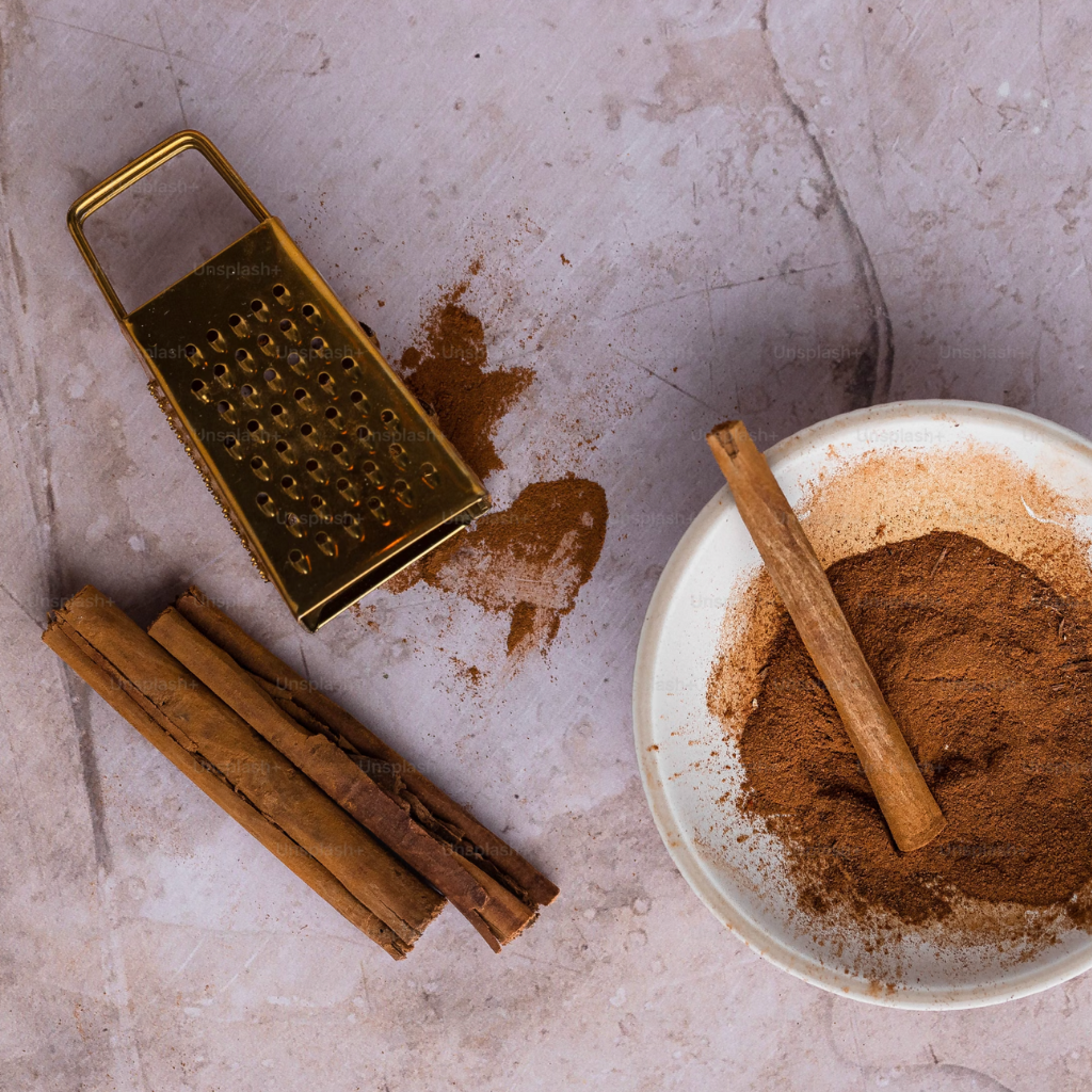 A warm, inviting scene featuring cinnamon sticks, a metal grater, and a bowl of finely ground cinnamon, evoking the rich and comforting essence of spice.