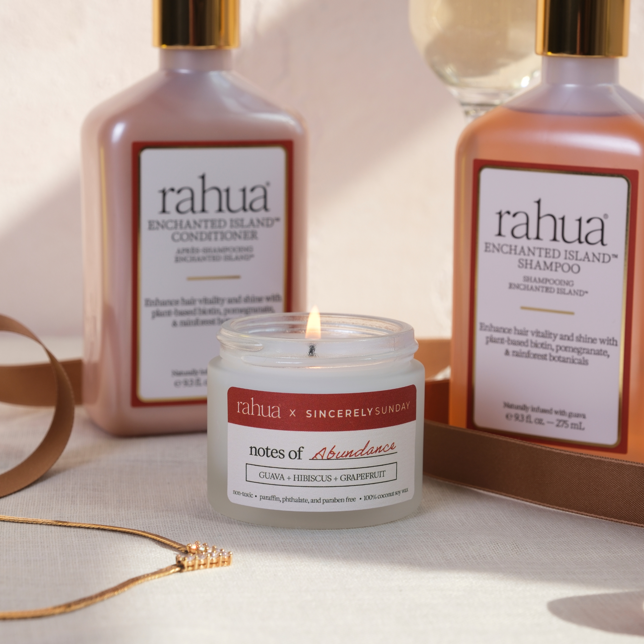 Rahua shampoo and conditioner bottles with a candle on a neutral background