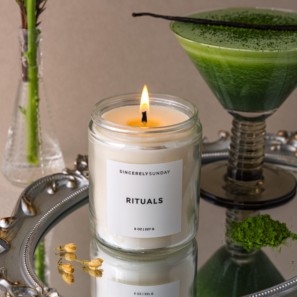 Candle labeled 'Sincerely Sunday Rituals' with a green cocktail in the background