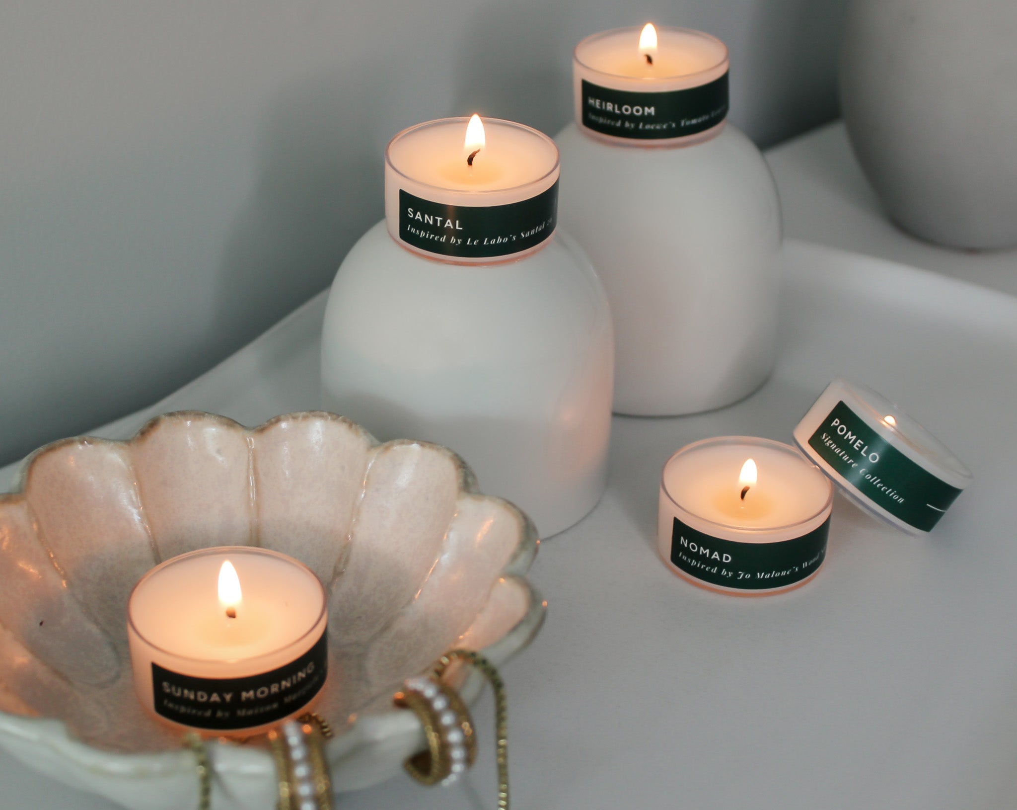 Set of lit tea light candles with green labels on a white surface