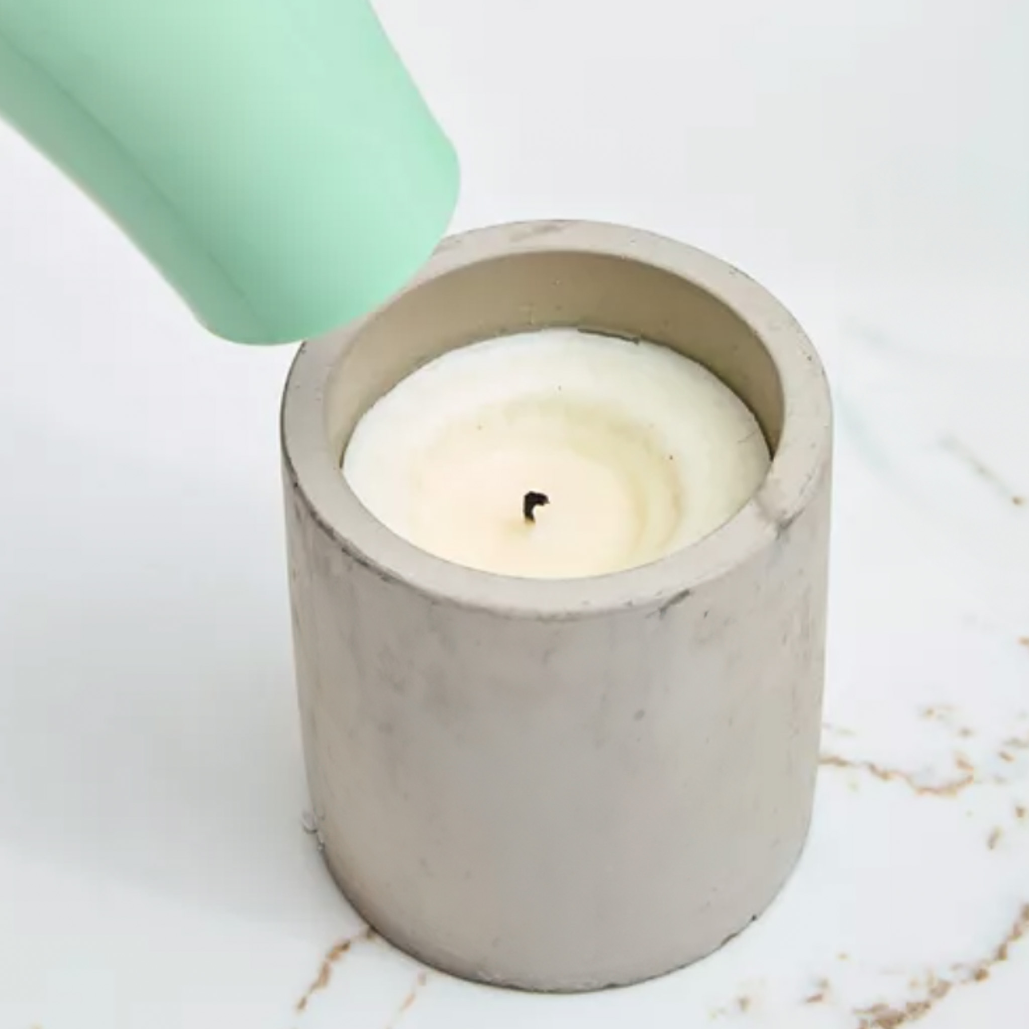 person using a hair dryer to melt the surface of a candle on a white background