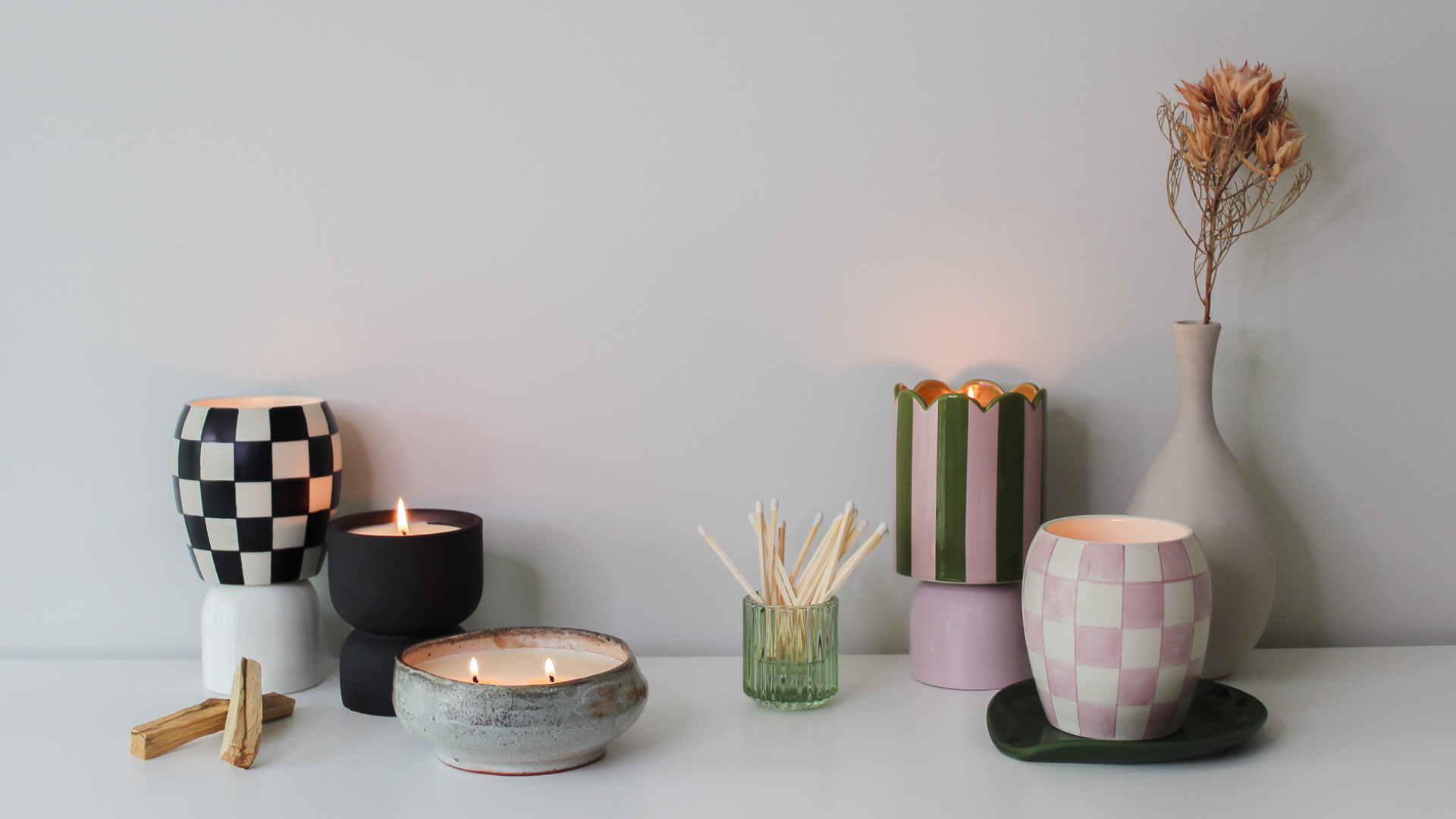 Collection of decorative candles on a white surface with a light gray background