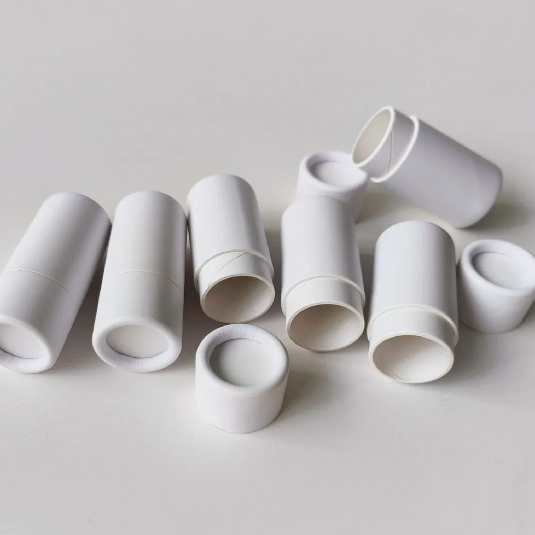 Six white cylindrical paper tubes of varying sizes scattered on a light gray background.
