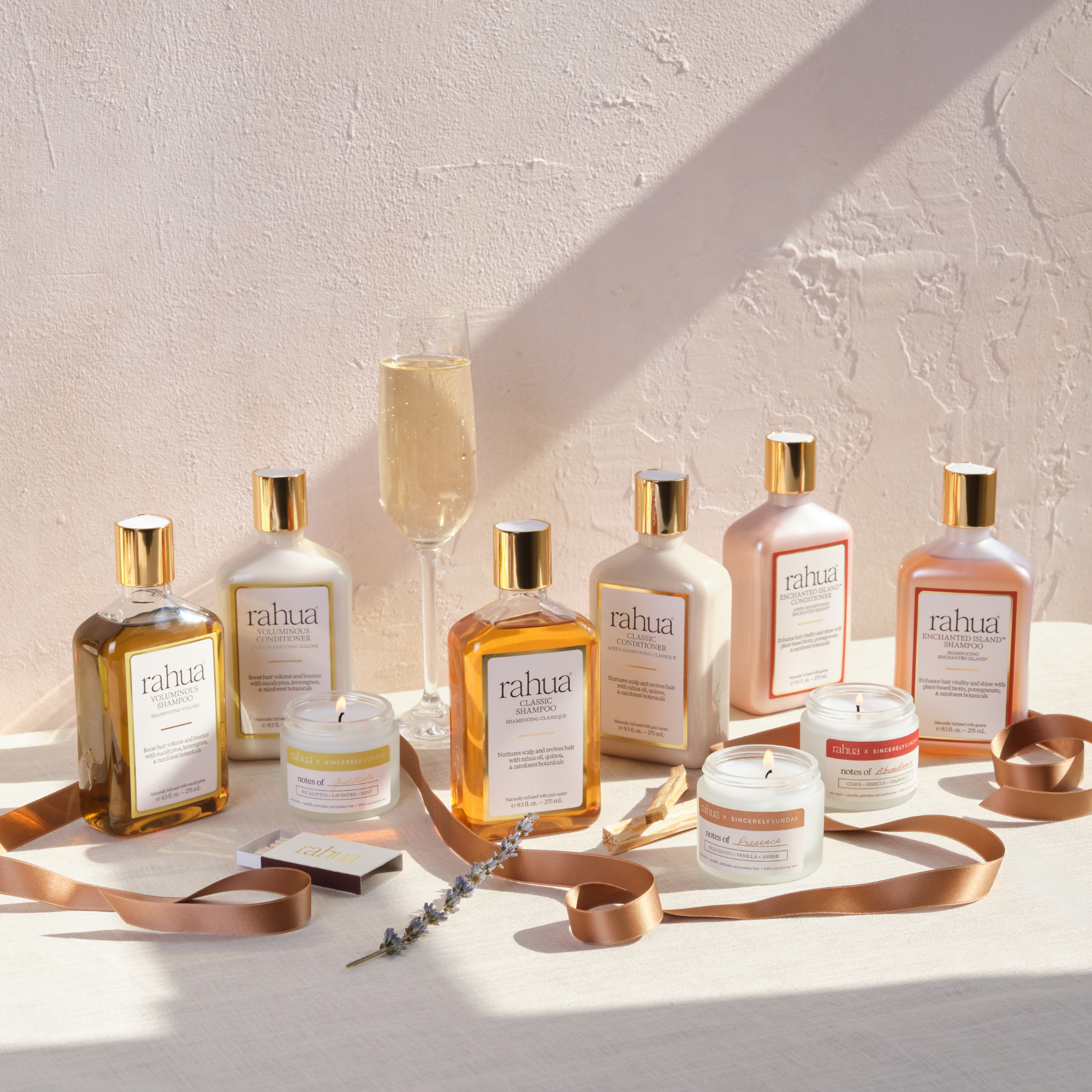 Collection of Rahua hair products with candles on a light surface with a neutral background