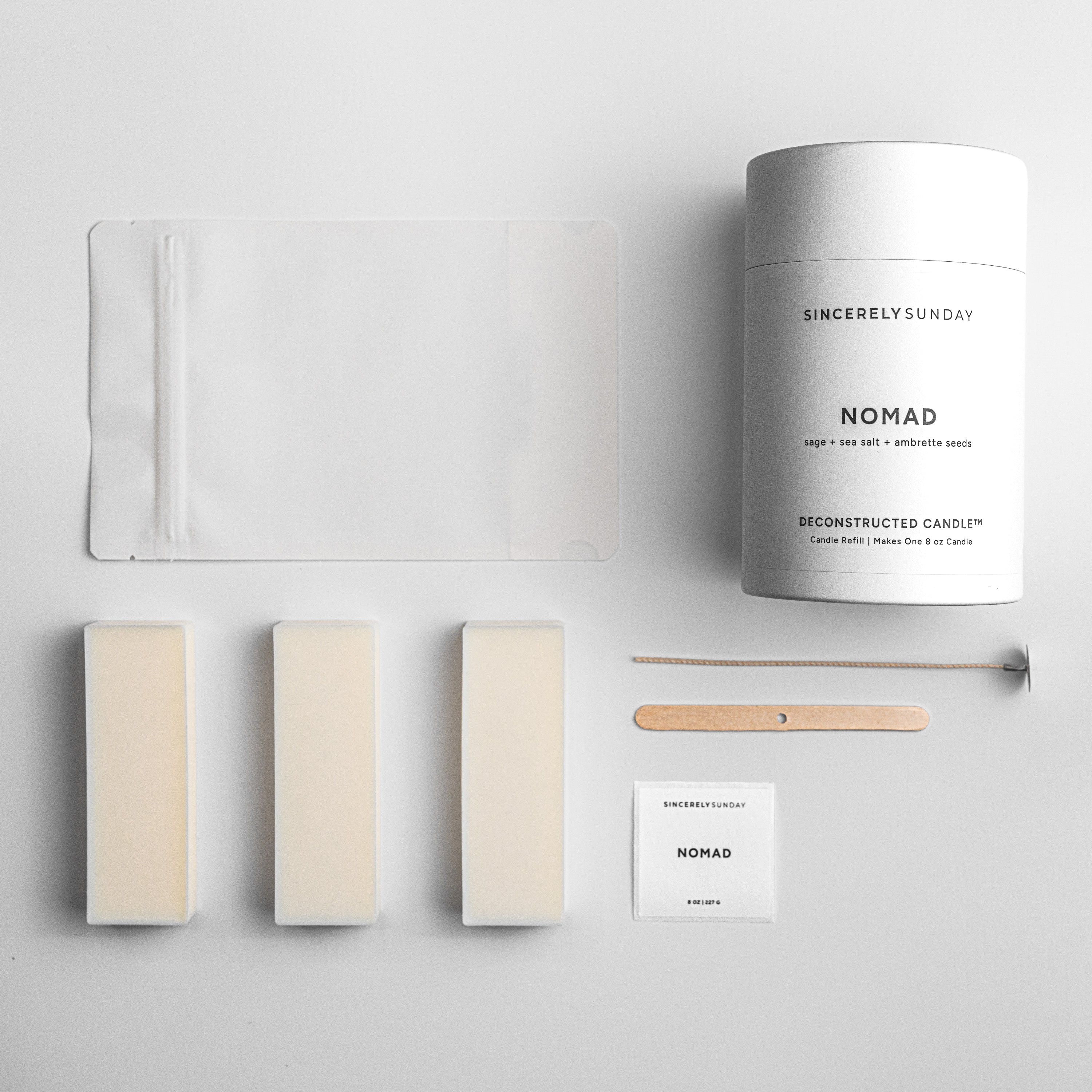 Sincerely Sunday candle with wax bars, a white pouch, wick, and wick holder on a light gray background
