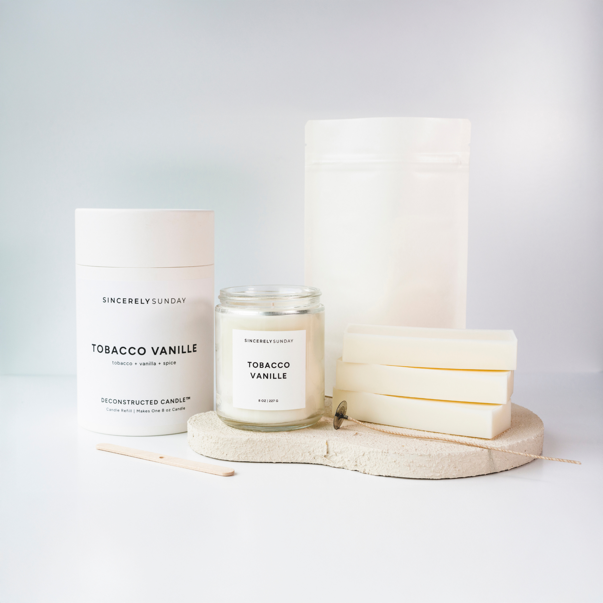 Sincerely Sunday candle refill kit next to a candle, wax bars, wick and wick holder, on a white background