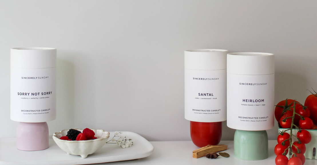 Three candle refill kits on a white surface, styled next to a bowl of berries and tomatoes in a decorative setup.