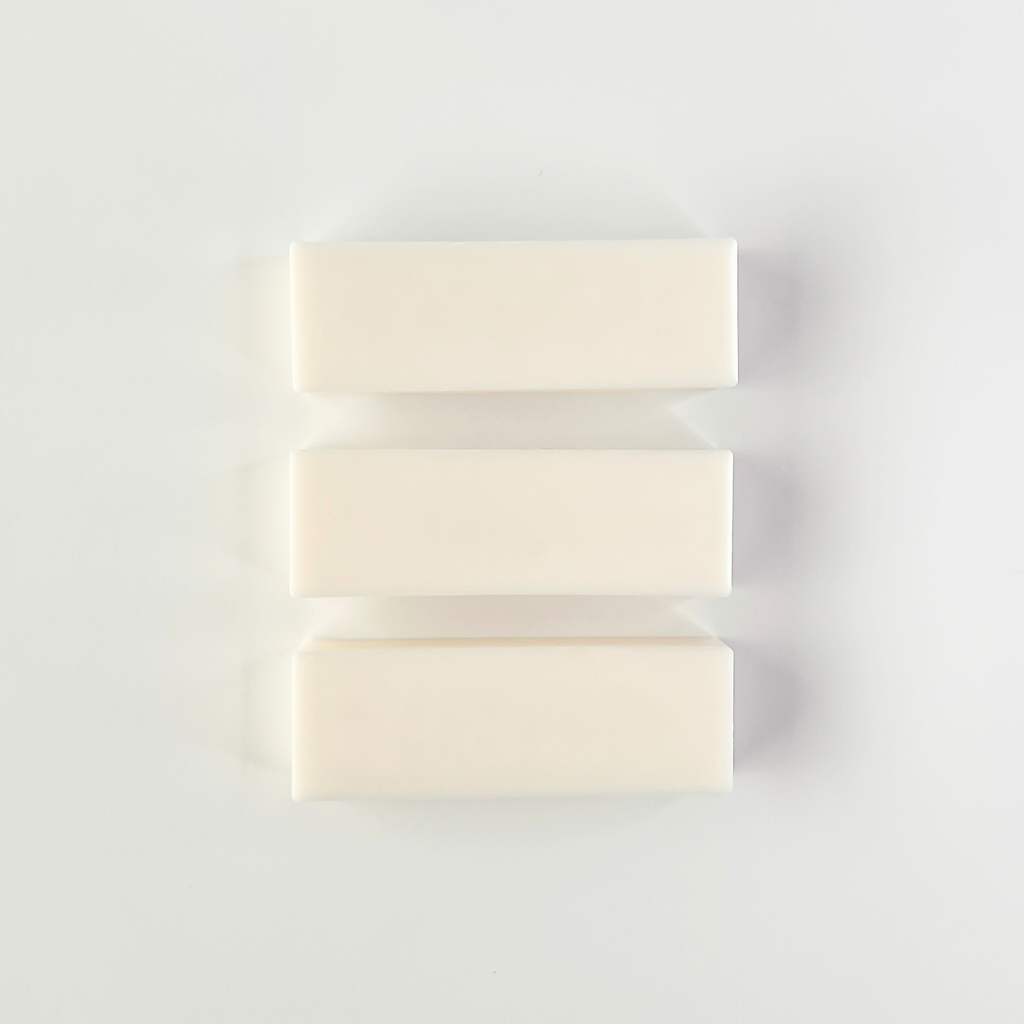 Three bars of white wax stacked on a light gray background