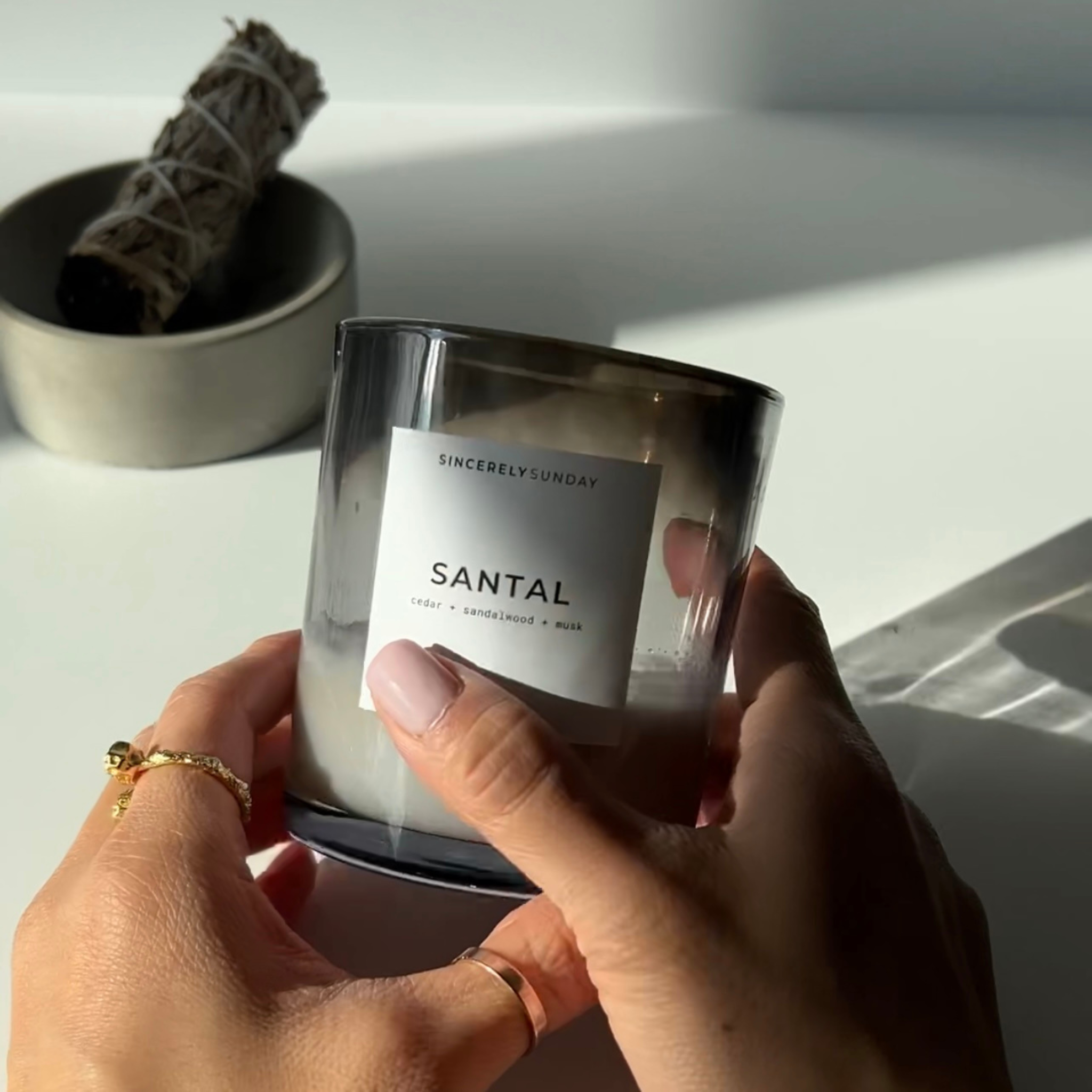 Person holding a “Santal” candle with black soot around the rim.