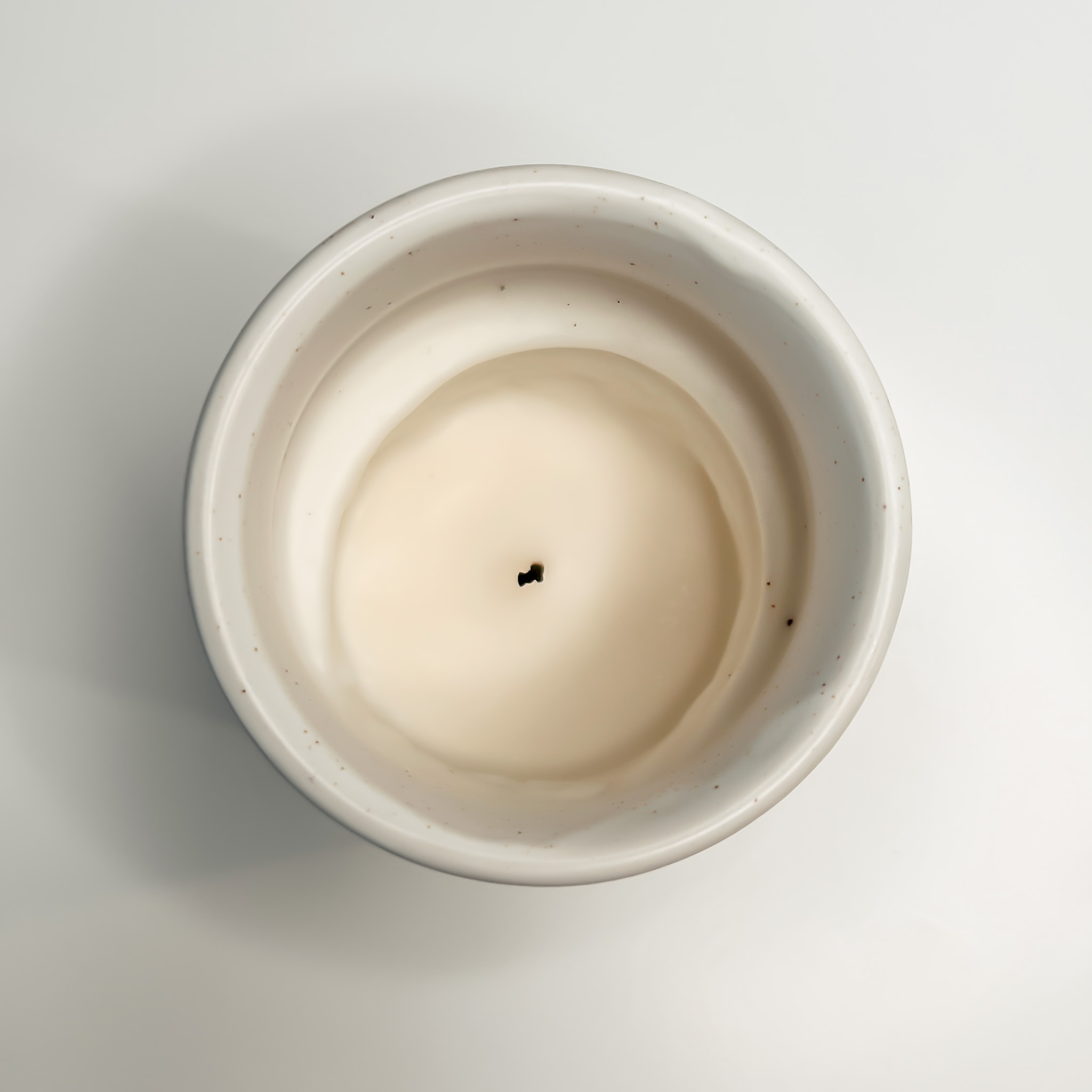 Candle with a significant amount of leftover wax along the sides on a white surface
